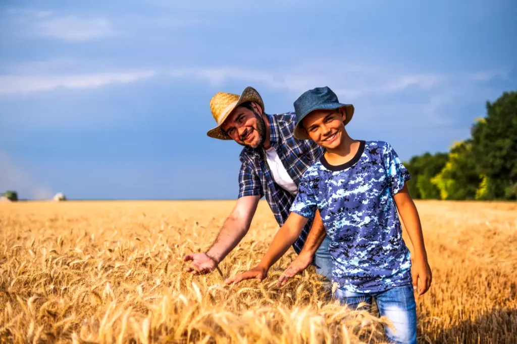 Pai e filha sorridentes, em uma plantação de trigo